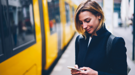 vrouw controleert telefoon voor instappen trein