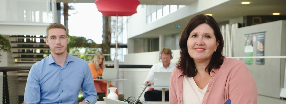 Man en vrouw in kantooromgeving kijken kijker aan